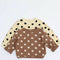 Two polka dot shirts, one beige with black dots and one brown with white dots, on a light blue background.